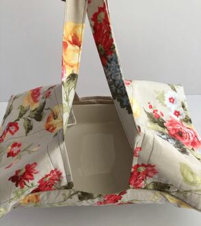 صورة حقيبة قماش لحمل الصواني وحافظات الطعام لونها بيج منقوش بالورد